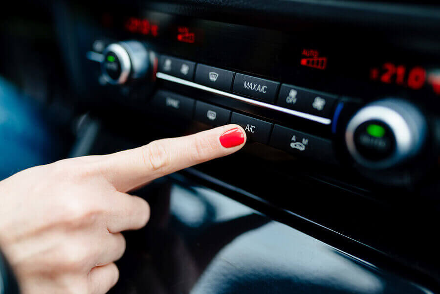 A woman going to press a Air Conditioning button on her car