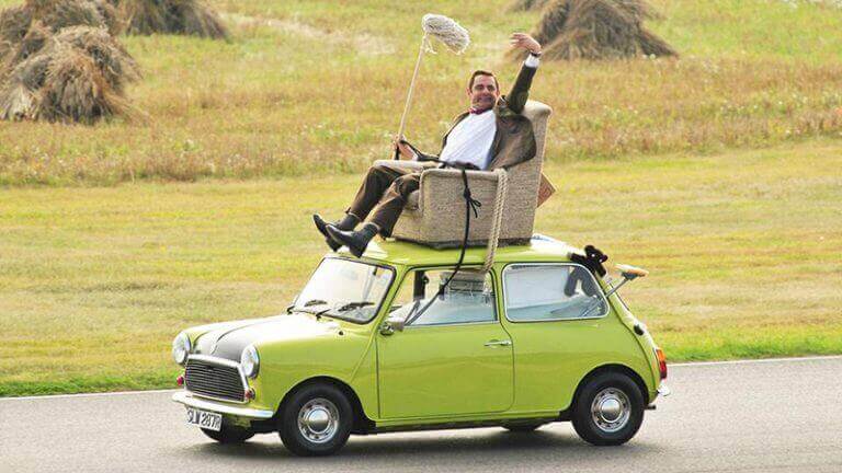 Mr Bean atop his green mini cooper in a arm chair